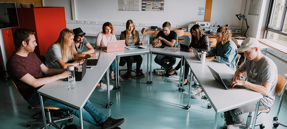 Studierende sitzen um einen runden Tisch im Mobile Lab.