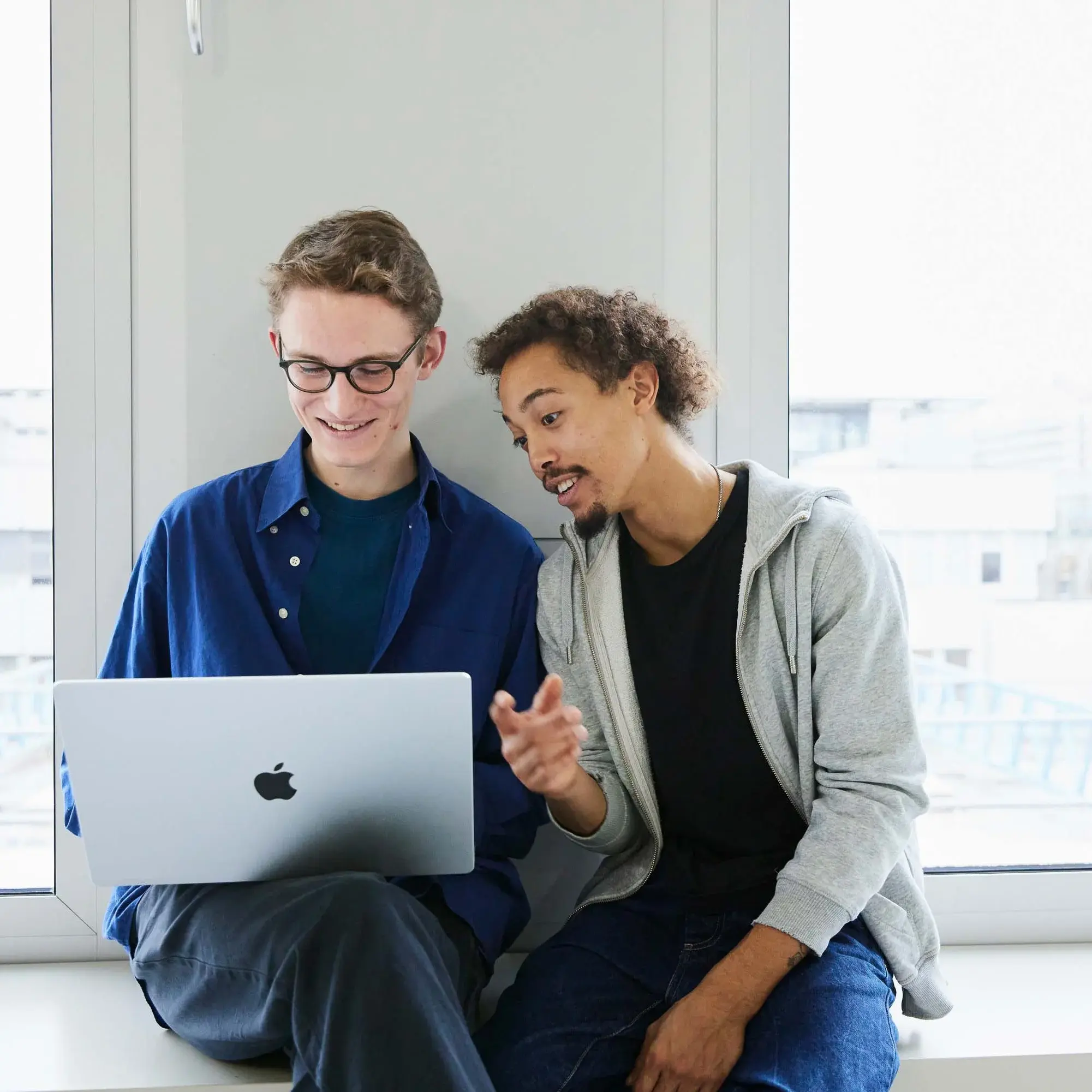 Two students are working on a laptop.