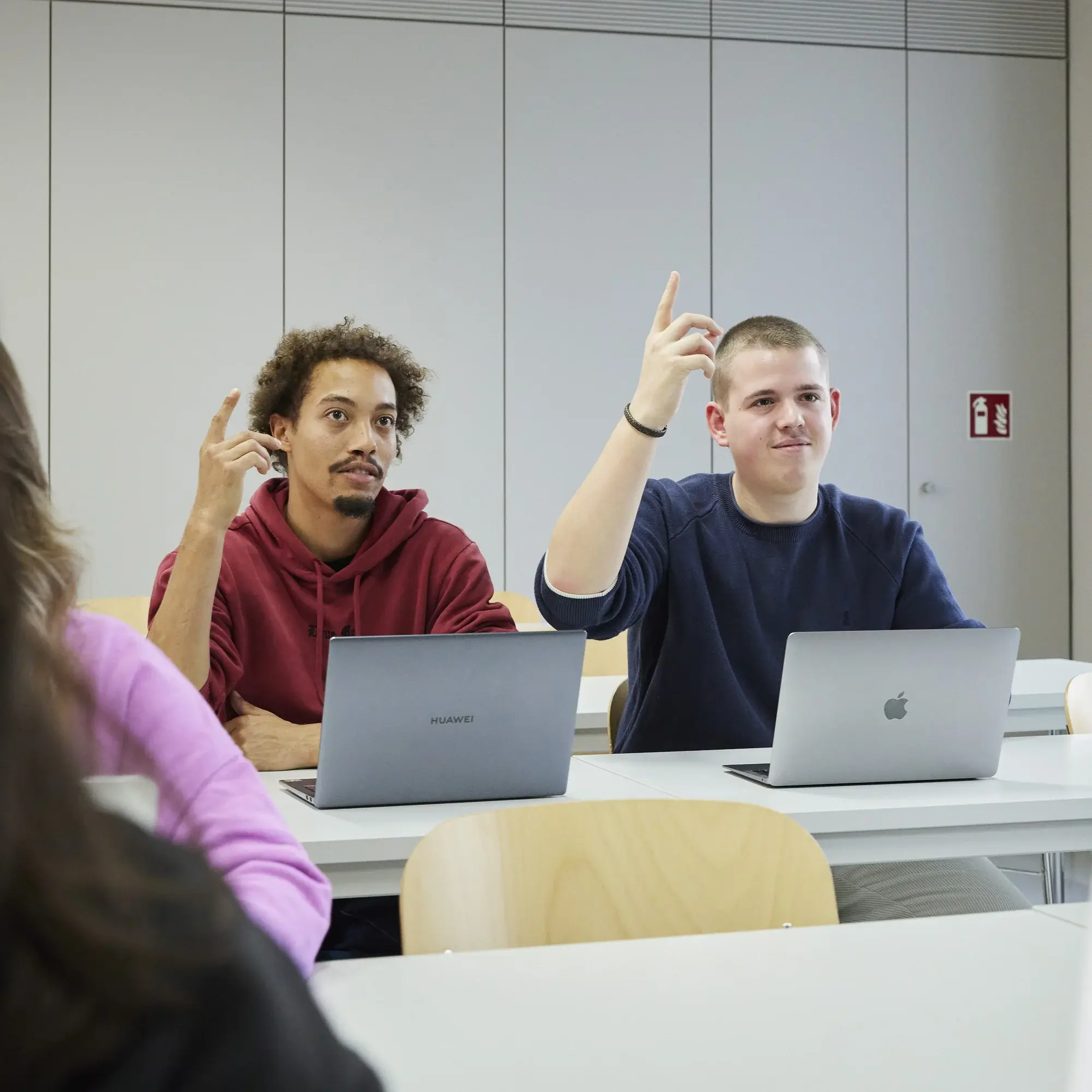 Two students raising their hands during the lecture.