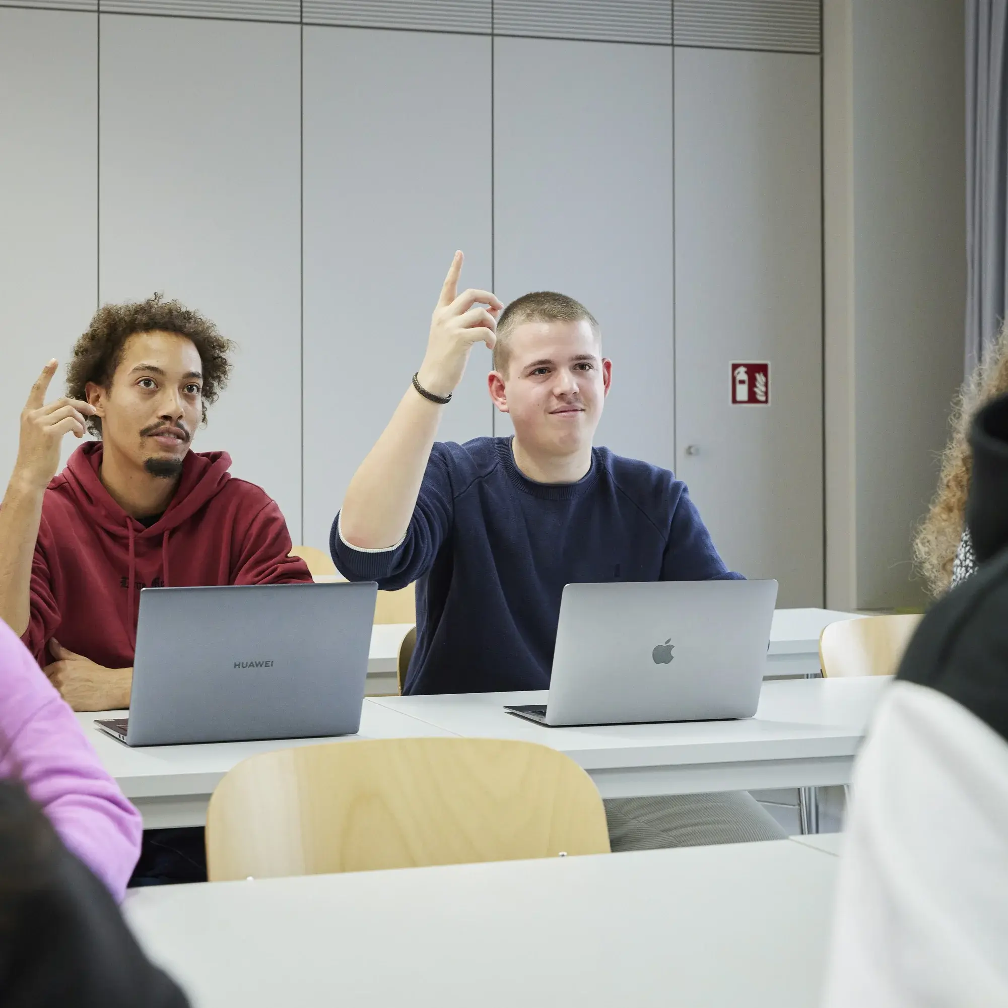 Two students raising their hands during the lecture.