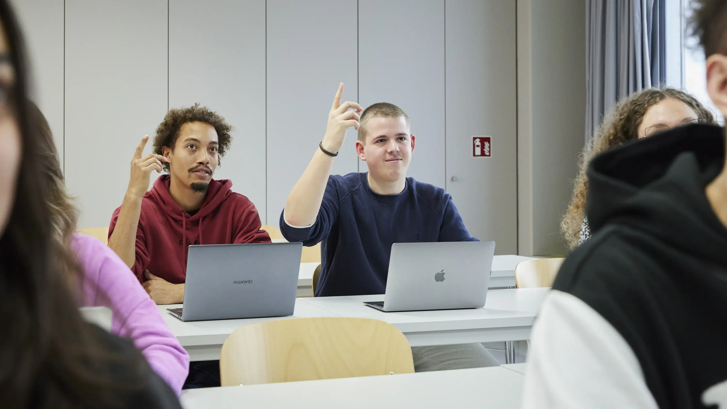 Two students raising their hands during the lecture.