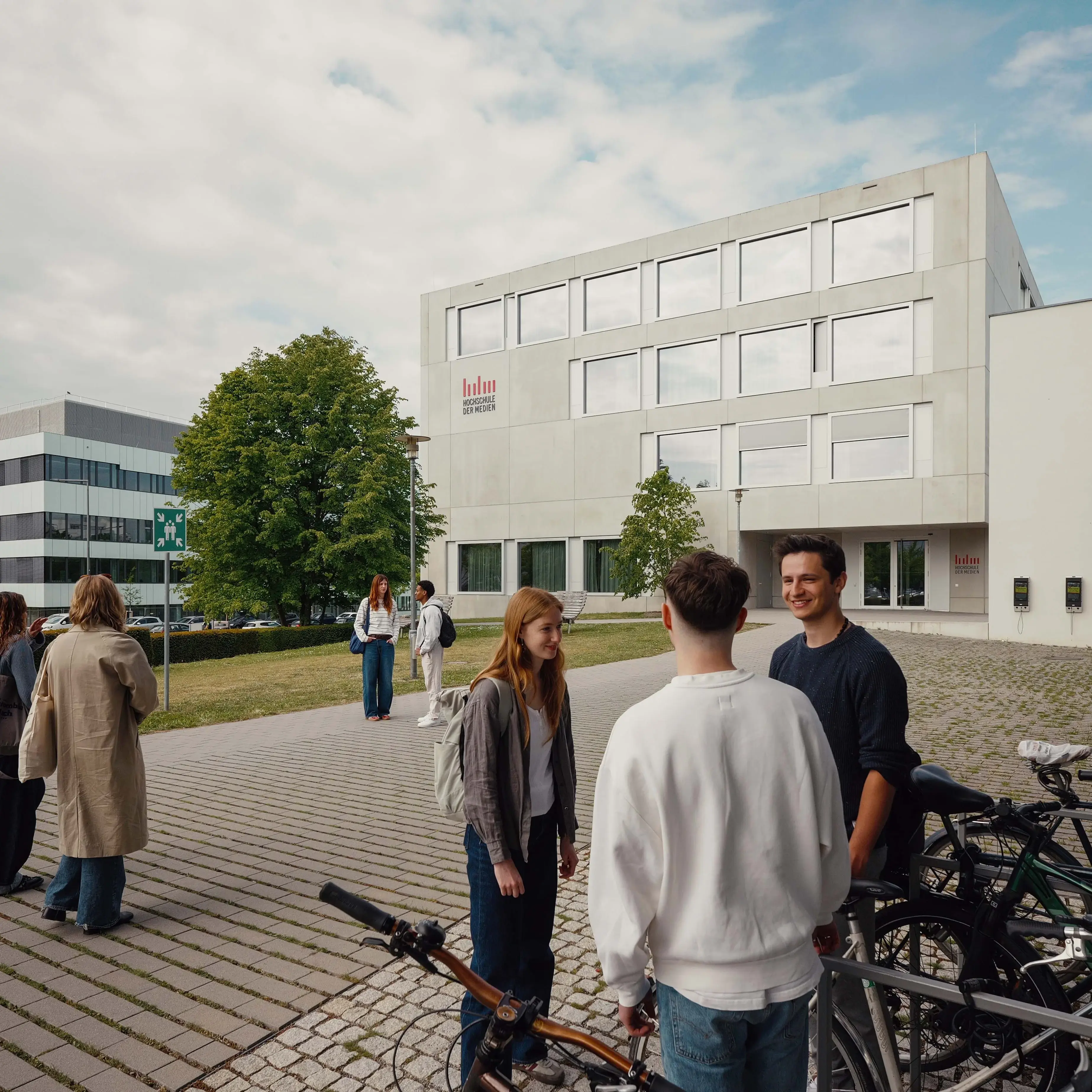 Studierende unterhalten sich vor dem sogenannten Würfel, einem Nebengebäude der Hochschule der Medien.