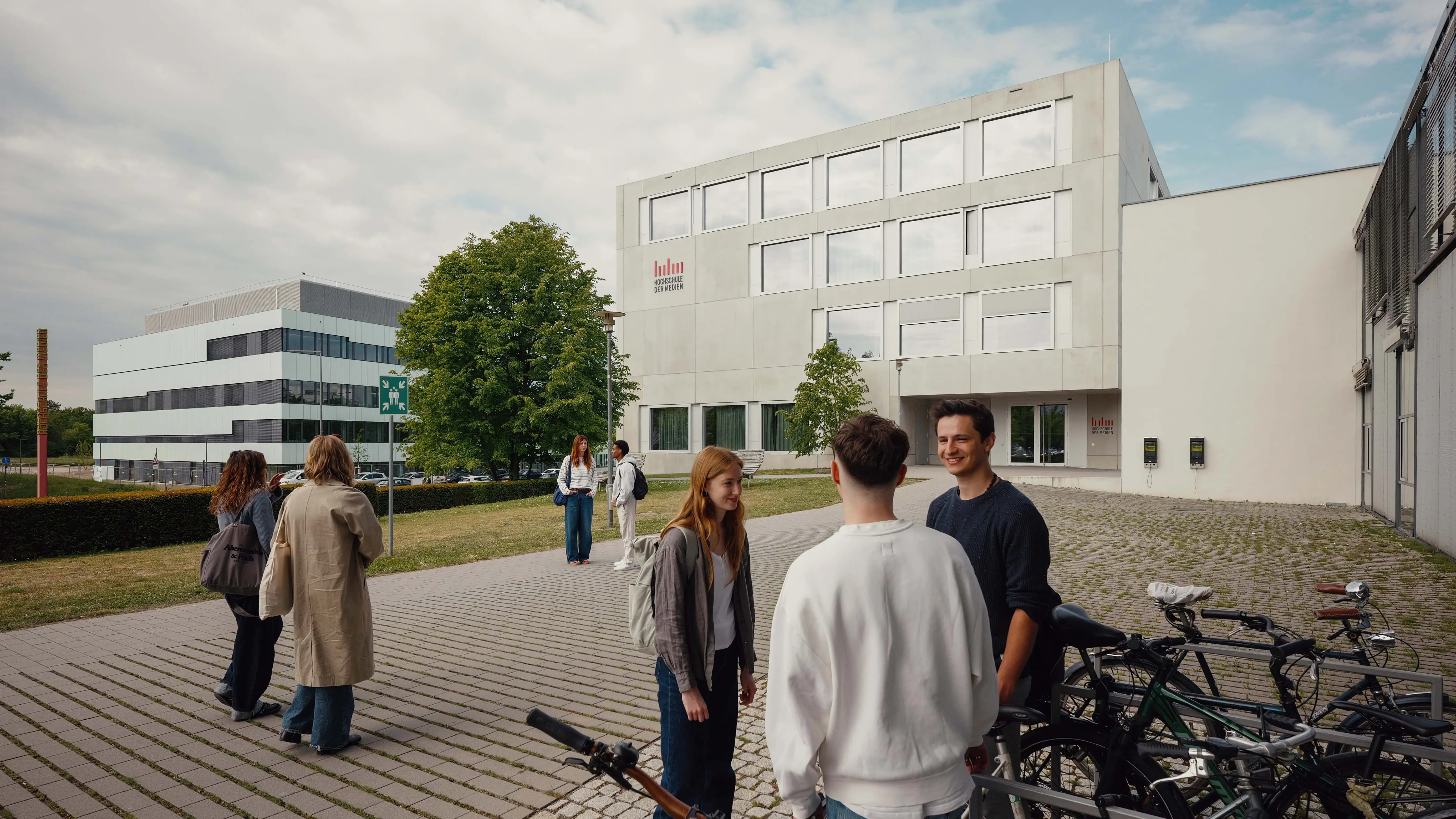 Studierende unterhalten sich vor dem sogenannten Würfel, einem Nebengebäude der Hochschule der Medien.