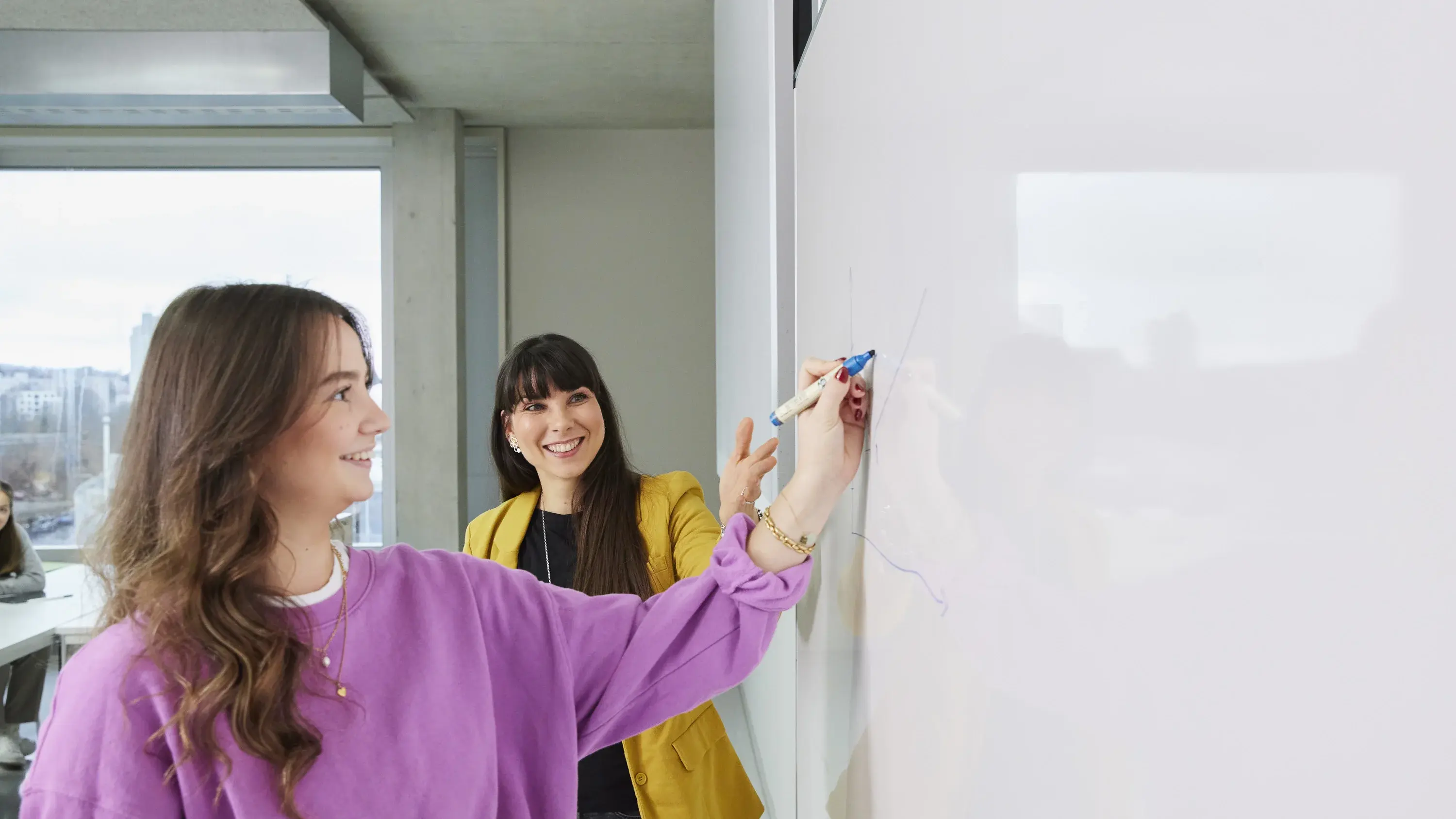 Eine Professorin hilft einer Studentin in einer Vorlesung.