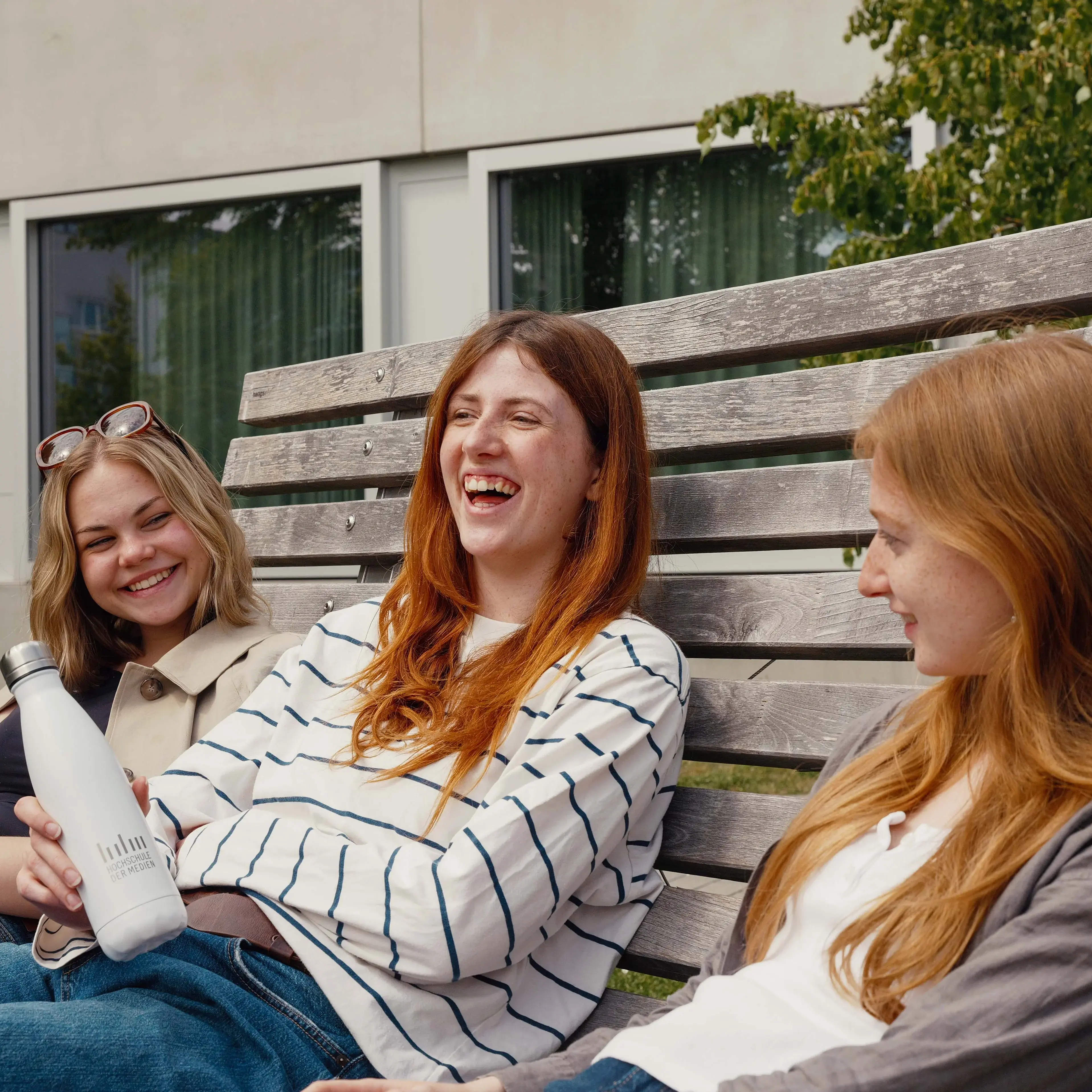 Studierende verbringen ihre Pause auf dem sonnigen Campus der Hochschule der Medien.