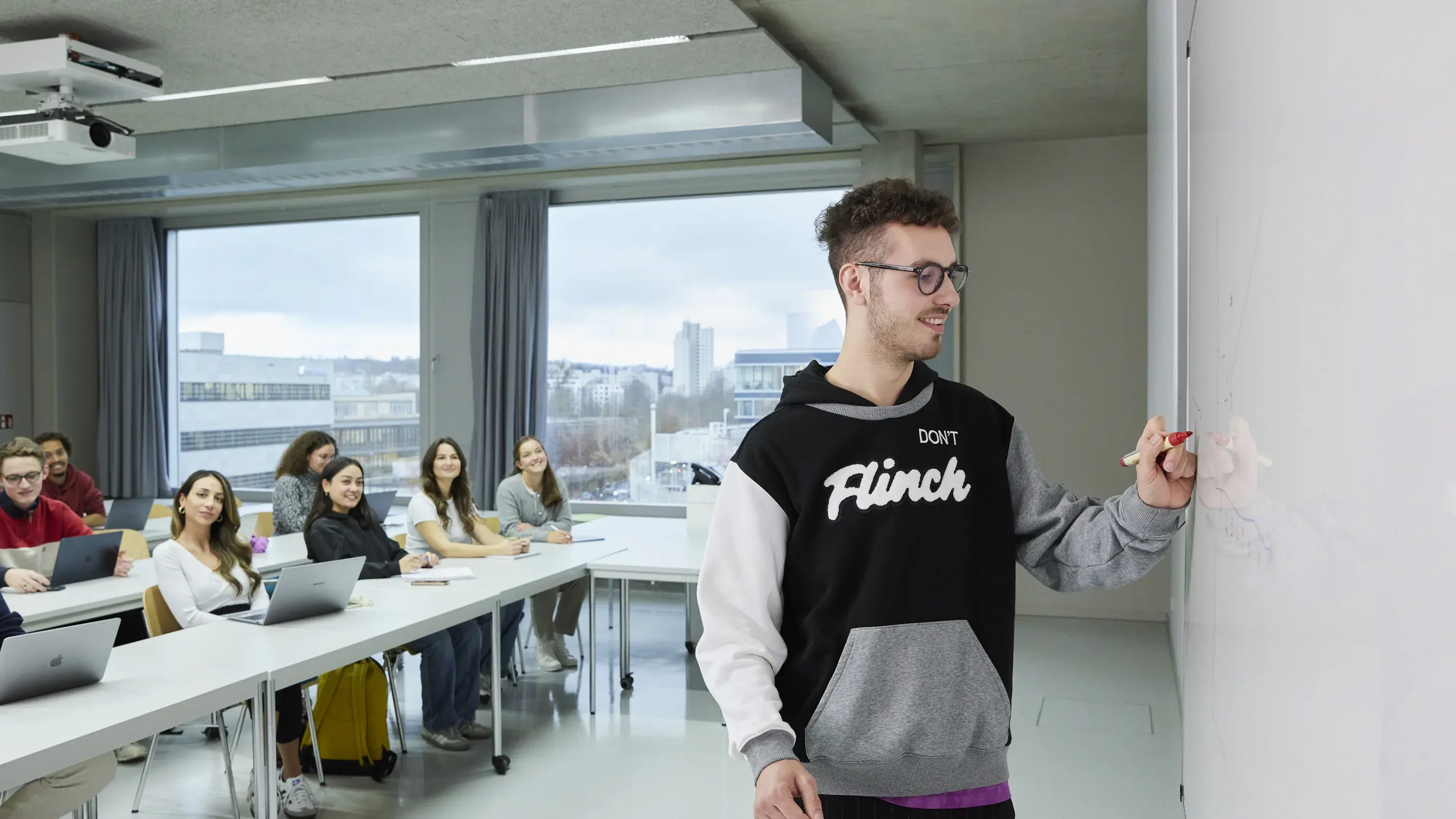 A student writing on the whiteboard with a pen during a lecture.