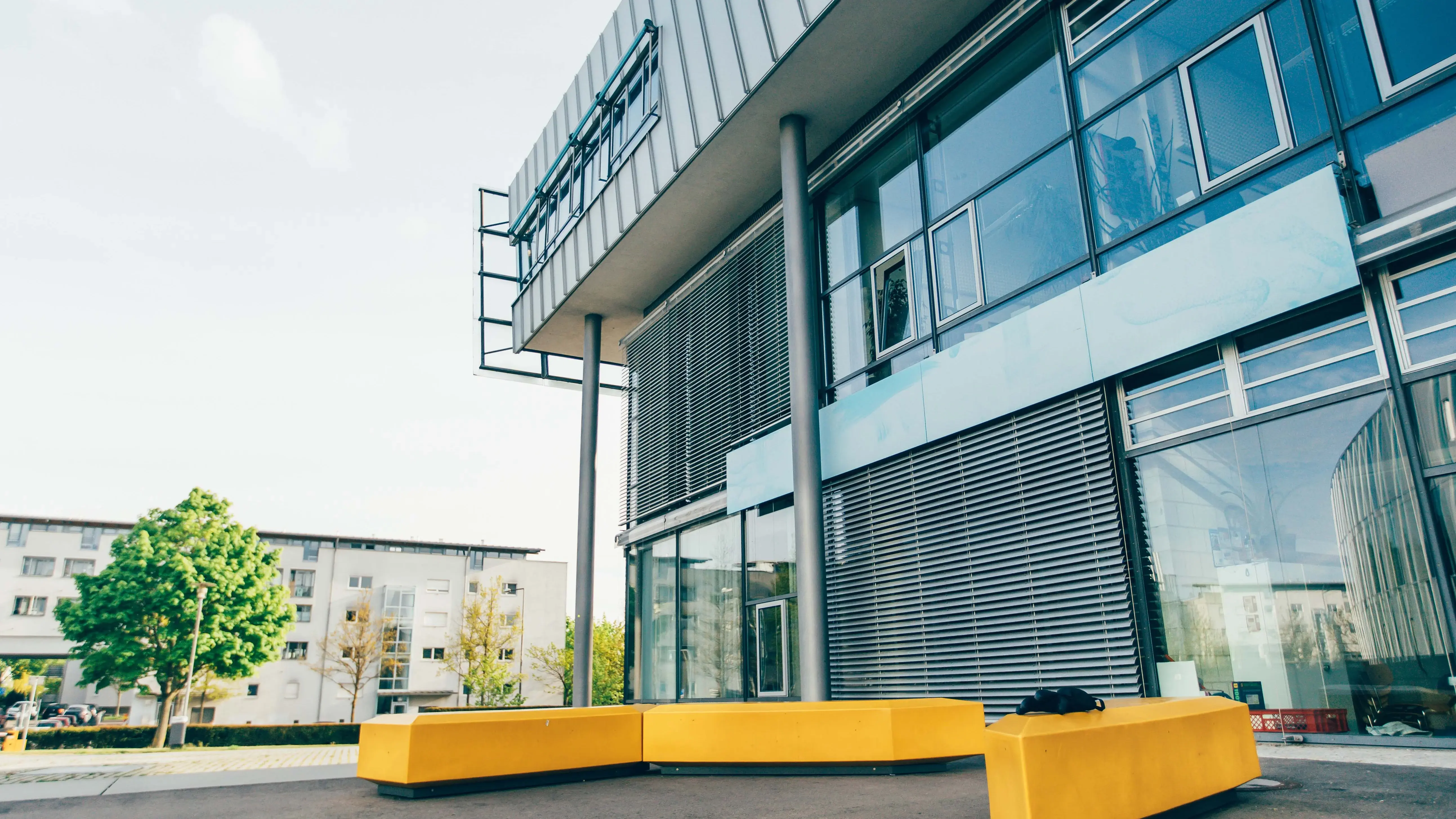 Gelbe Sitzgelegenheiten vor dem Hauptgebäude der Hochschule der Medien.