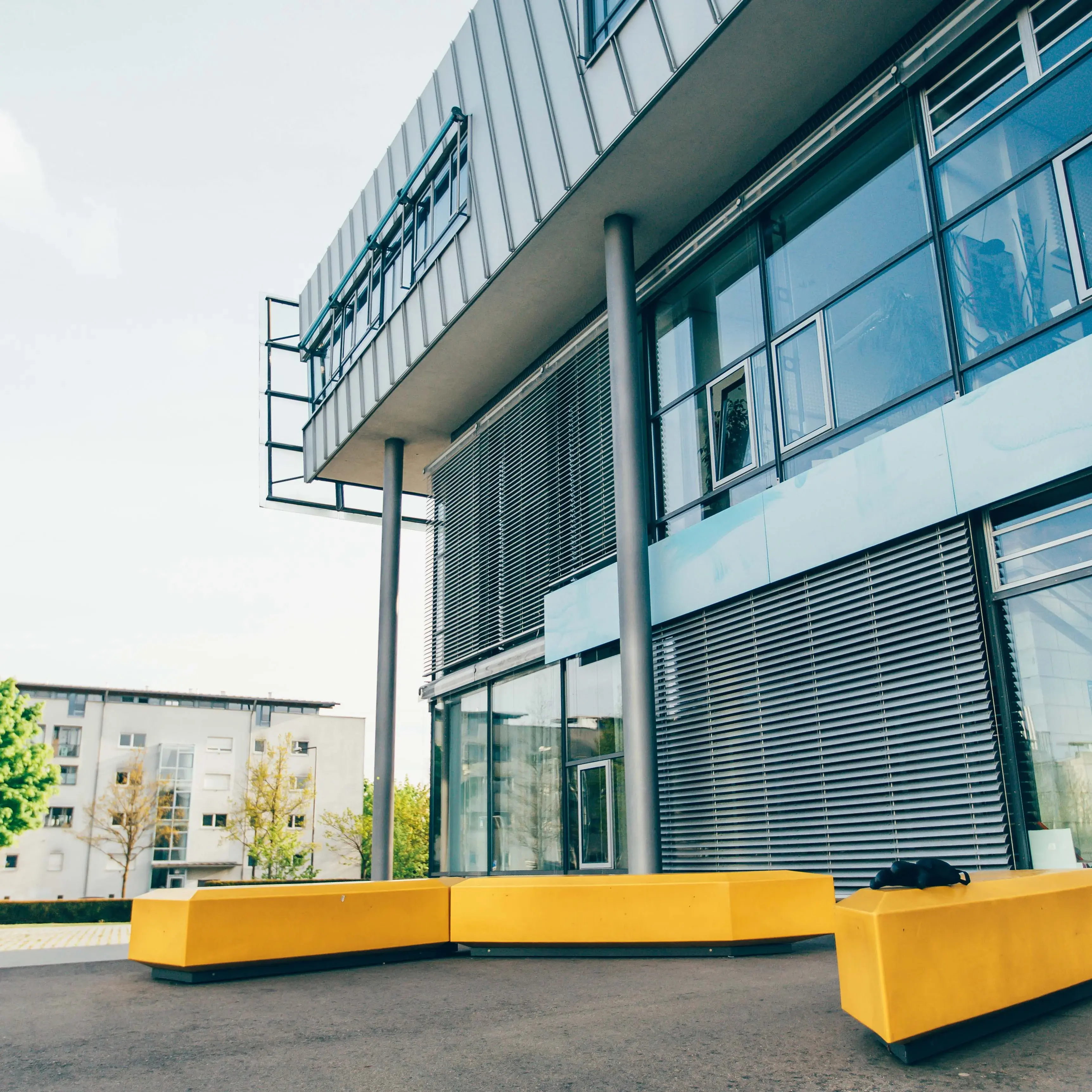 Gelbe Sitzgelegenheiten vor dem Hauptgebäude der Hochschule der Medien.