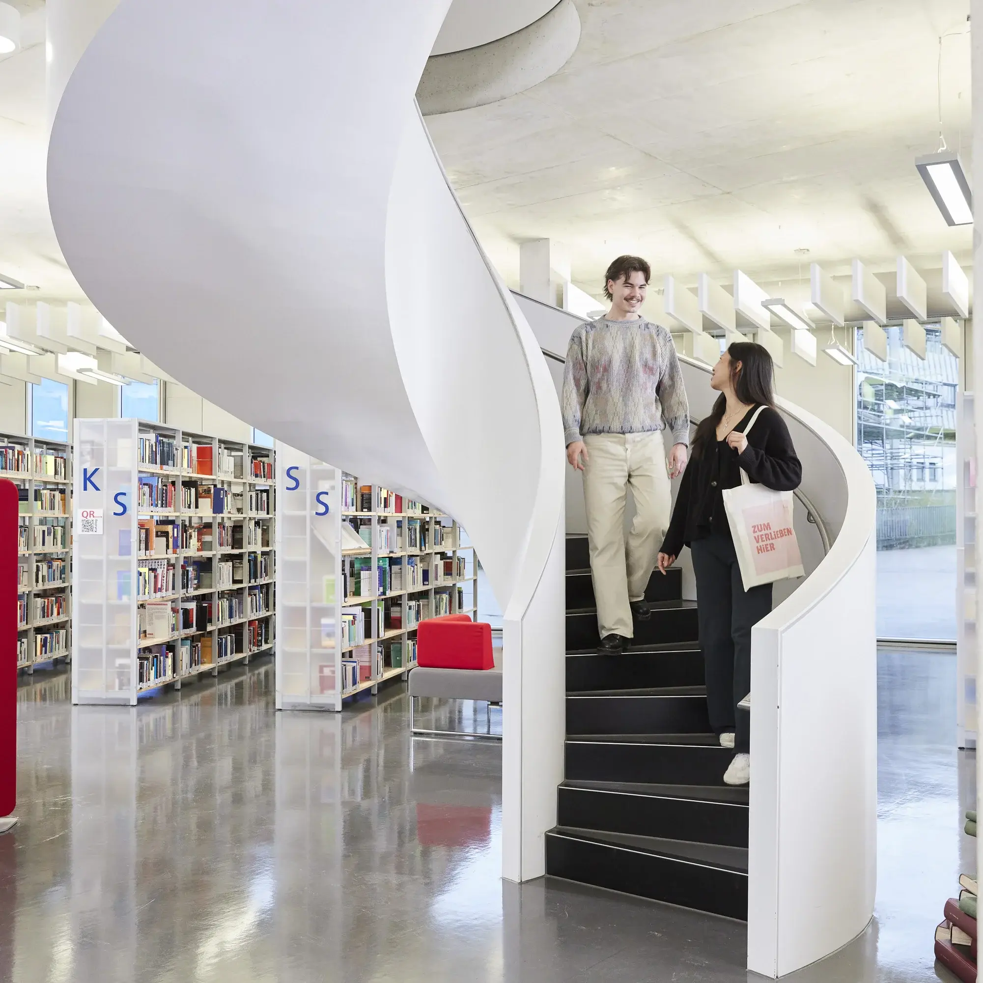 Students on the stairs in the library of the University of Media.