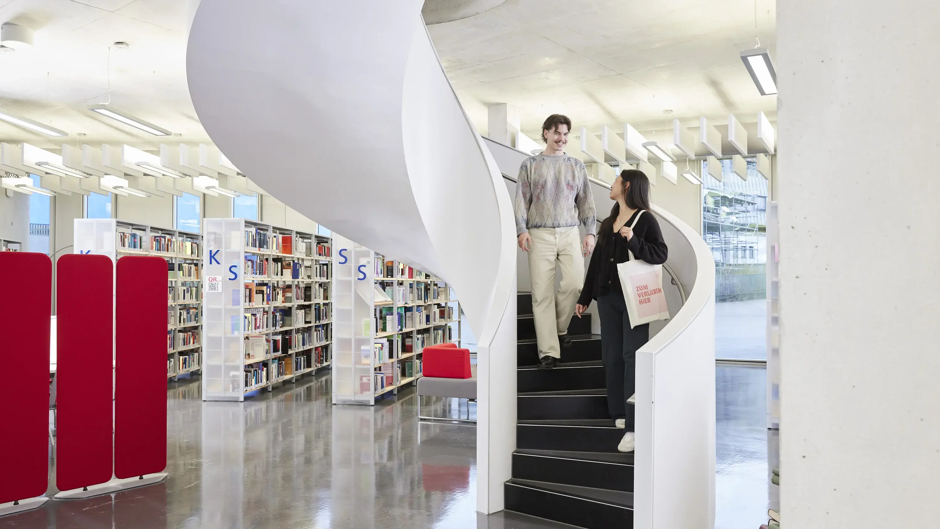 Students on the stairs in the library of the University of Media.