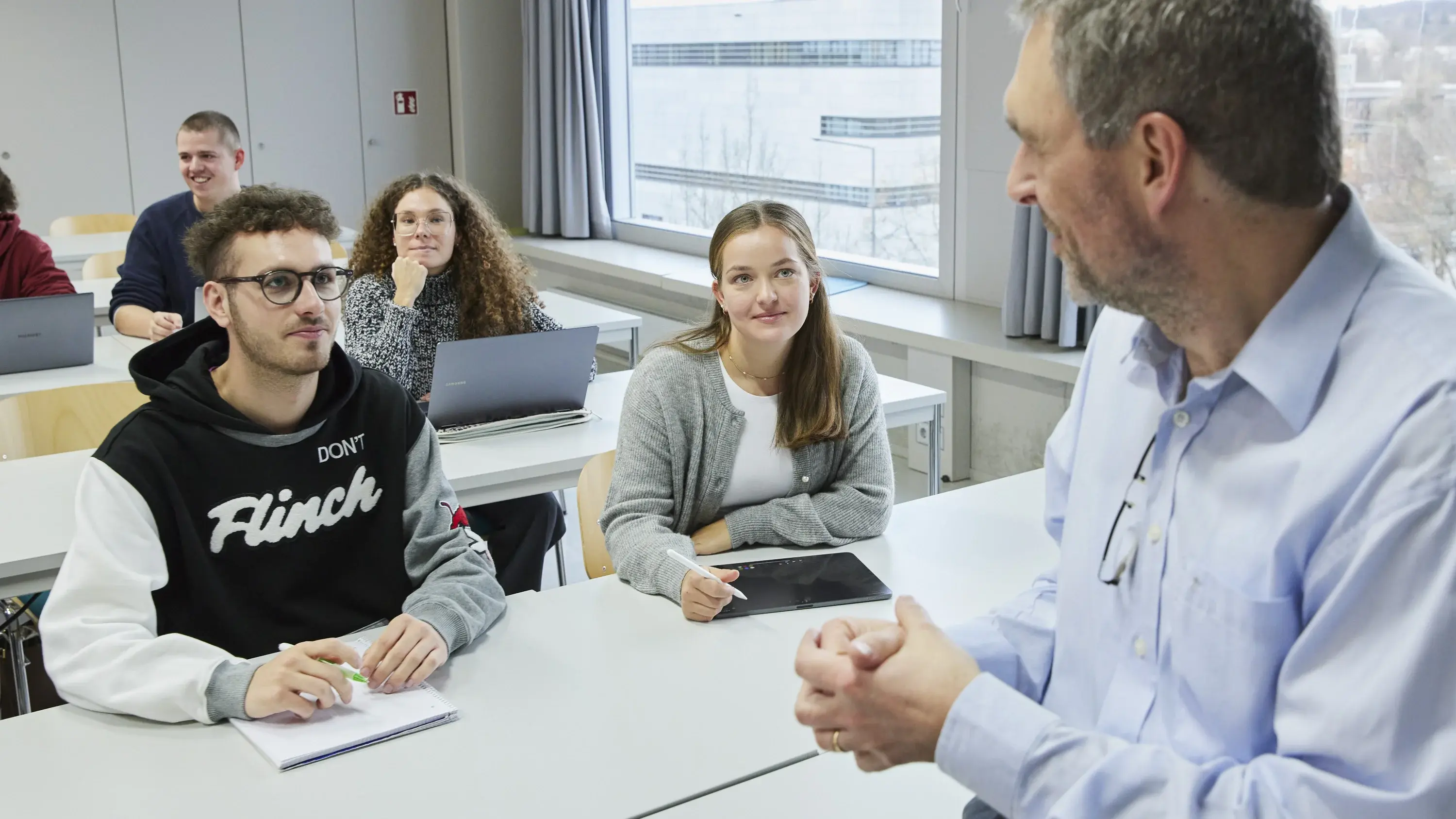 A professor is talking to some students during a lecture.