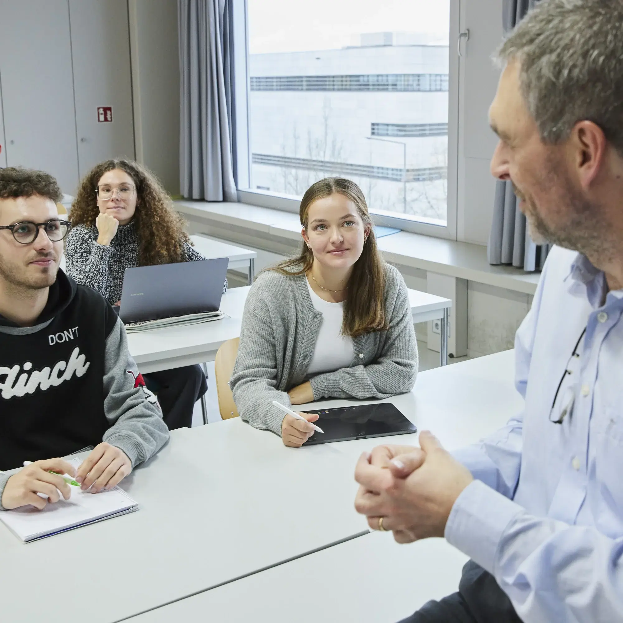 A professor is talking to some students during a lecture.