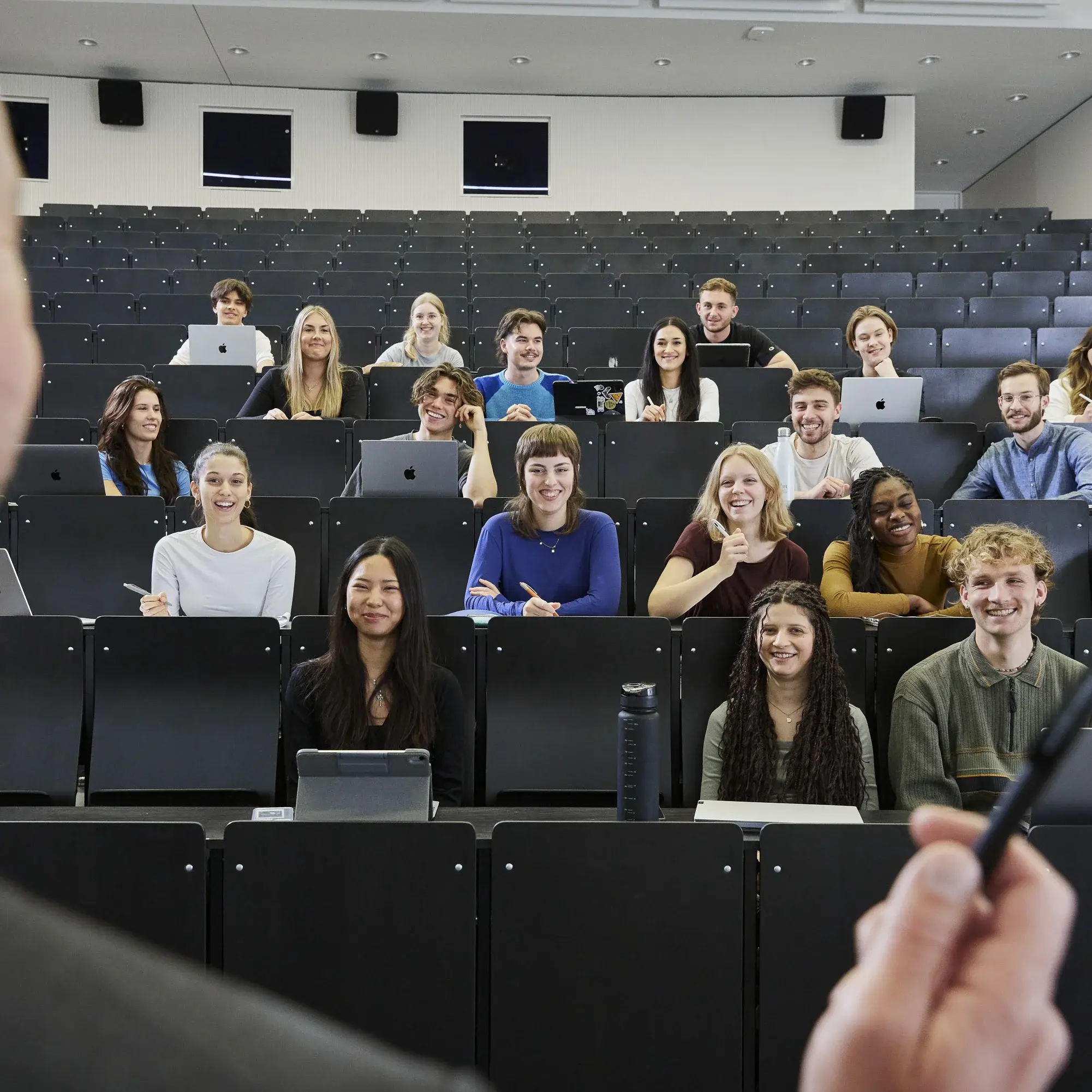 Professor standing in front of students in a lecture hall.