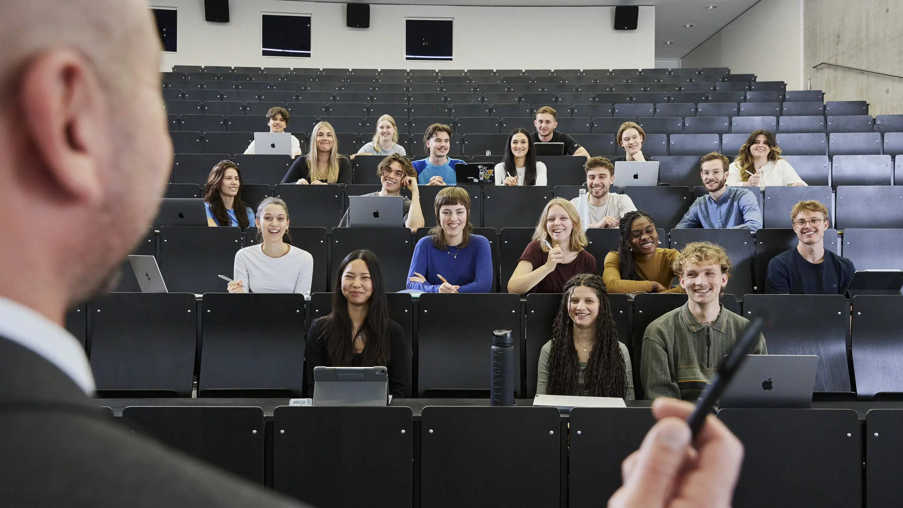 Professor standing in front of students in a lecture hall.