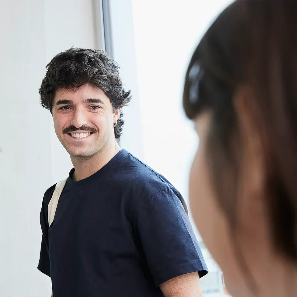 A student smiles at another student.