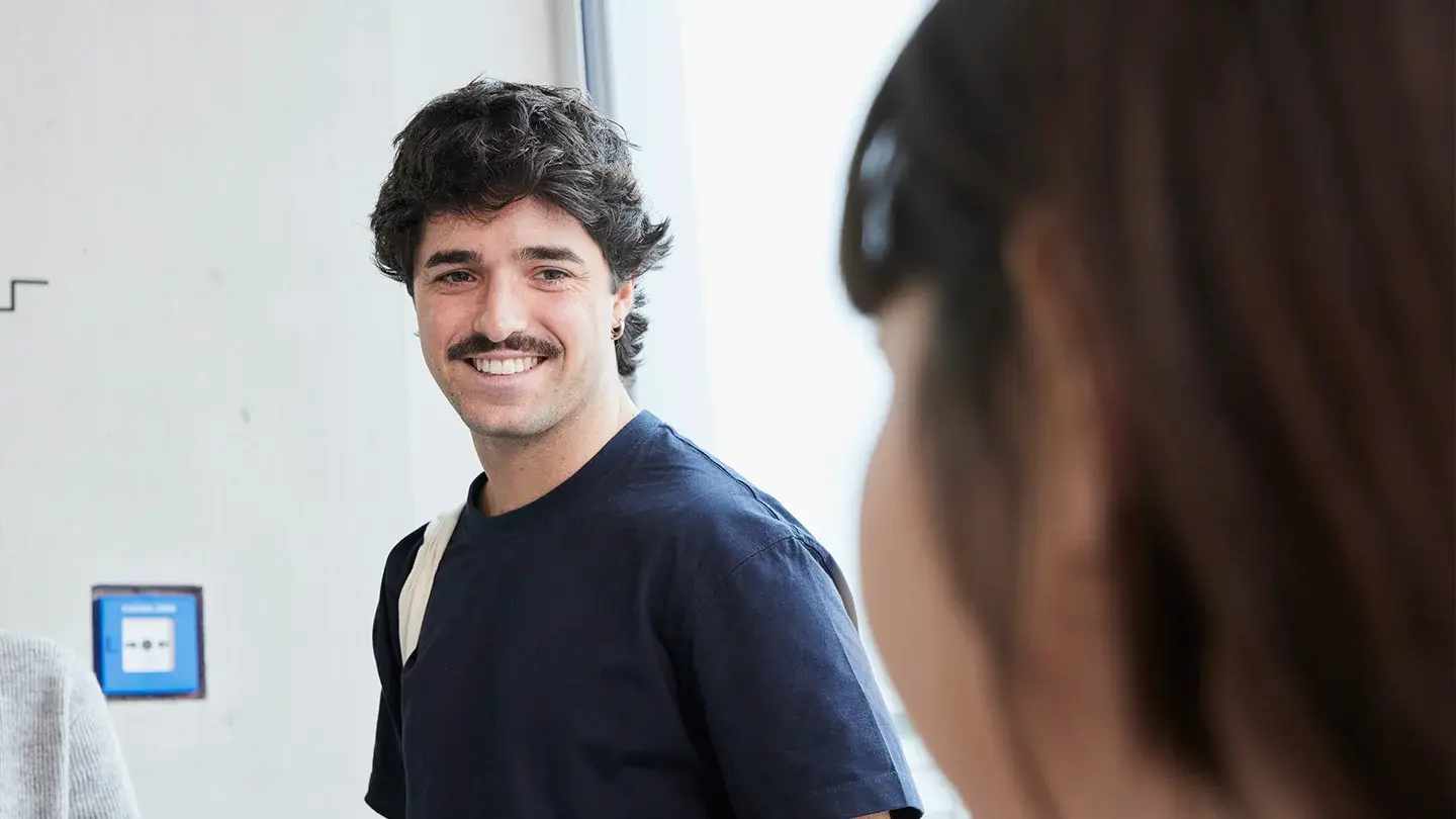 A student smiles at another student.
