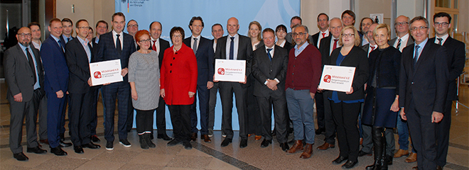 Brigitte Zypries, Bundesministerin für Wirtschaft und Energie (Mitte), Prof. Dr. Michael Burmester (mit Schild, Mitte) und Dr. Katharina Zeiner (rechts neben Prof. Dr. Michael Burmester), Foto: BMWi/Andreas Mertens